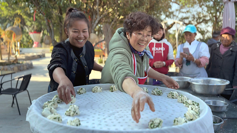 【2】旅居者趙發(fā)英（圖左二）教曼海村村民做花卷。陶思源-攝